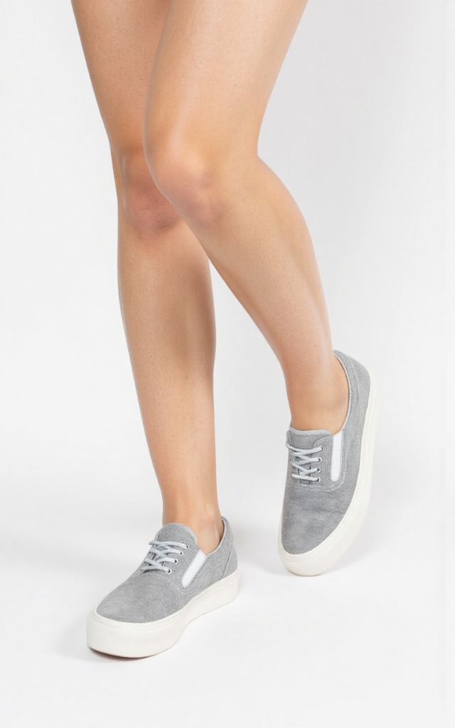 A female model wearing casual shoes, against a white background, with a close   up of the feet